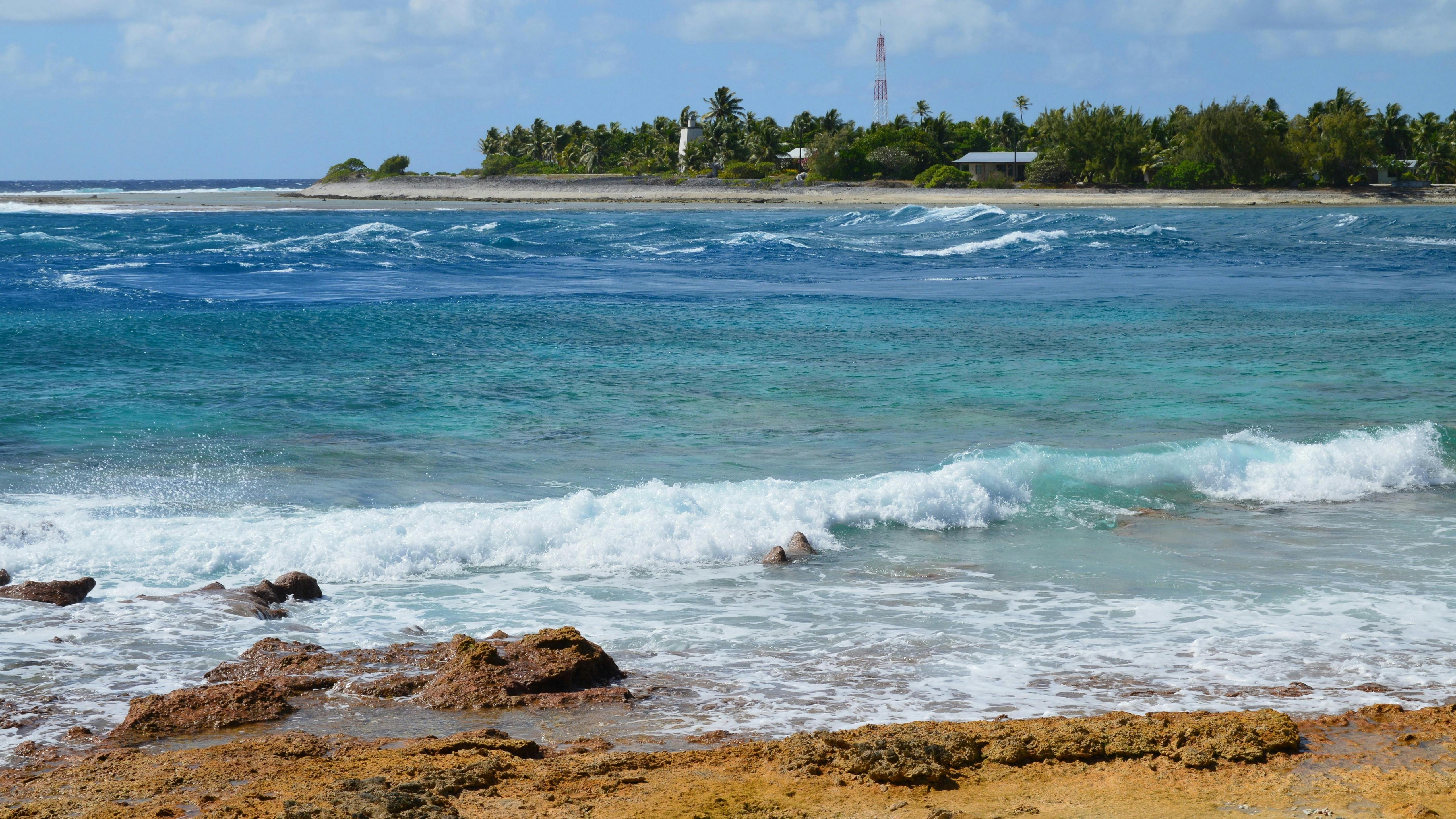 Aerial look at rugged volcanic shoreline and surf around Nauru, program overview feature photov